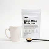 ALL7 Lion's Mane Mushroom powder with the ALL7 black measuring spoon and a mug